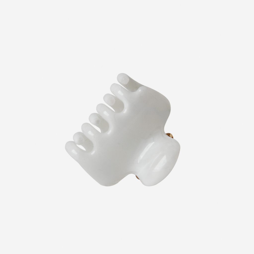 white medium hair claw photographed on it's side, on an off white background
