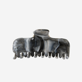 Grey, black and blue marbled hair claw on an off white background