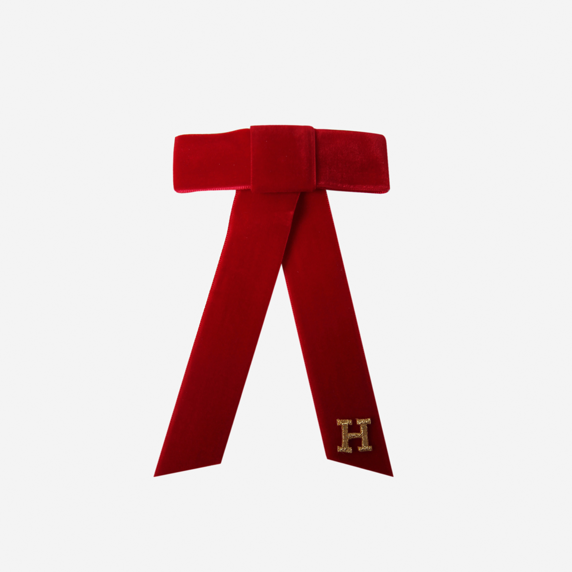 Red velvet bow with a gold letter 'H' on an off white background