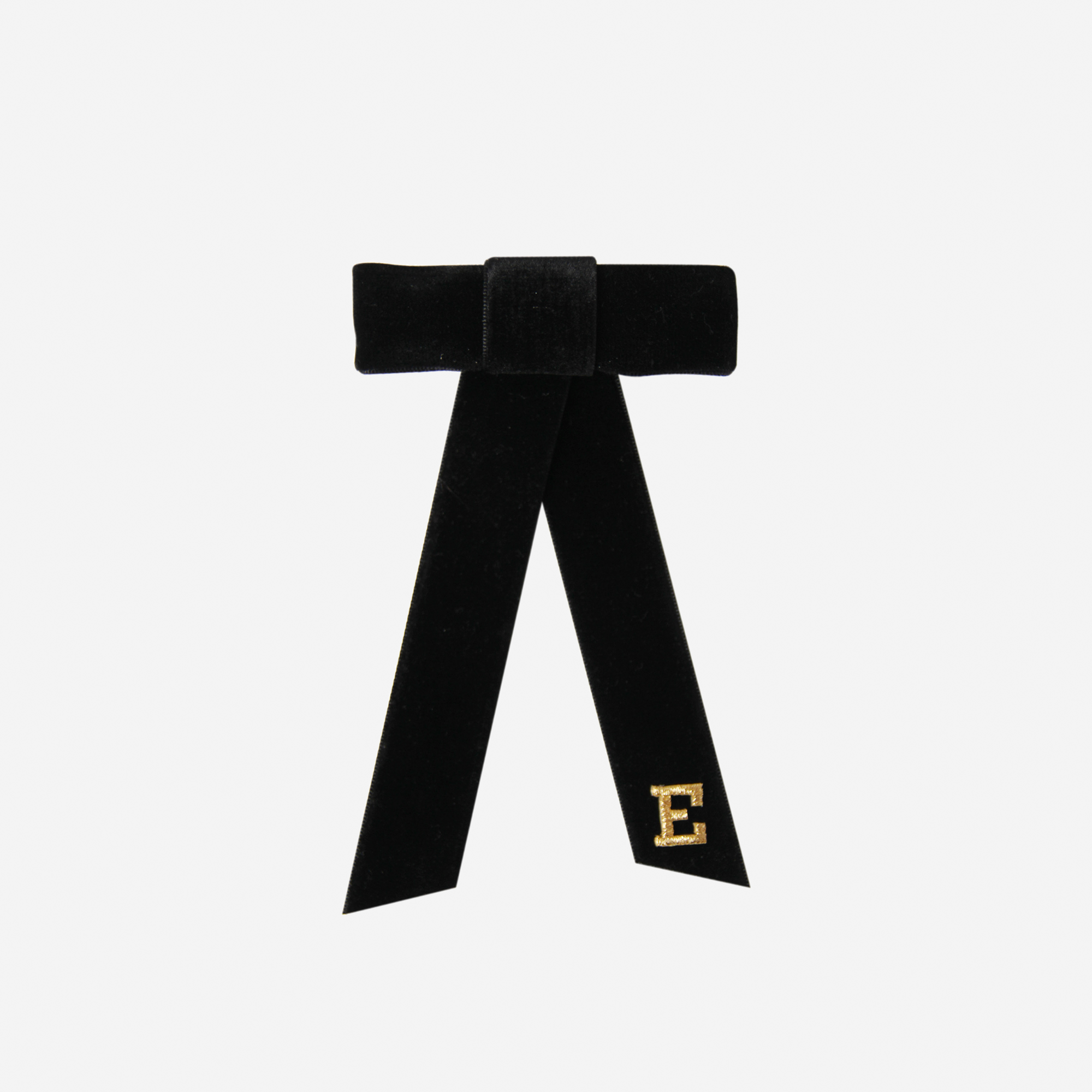 Black velvet bow with a gold letter 'E' on an off white background