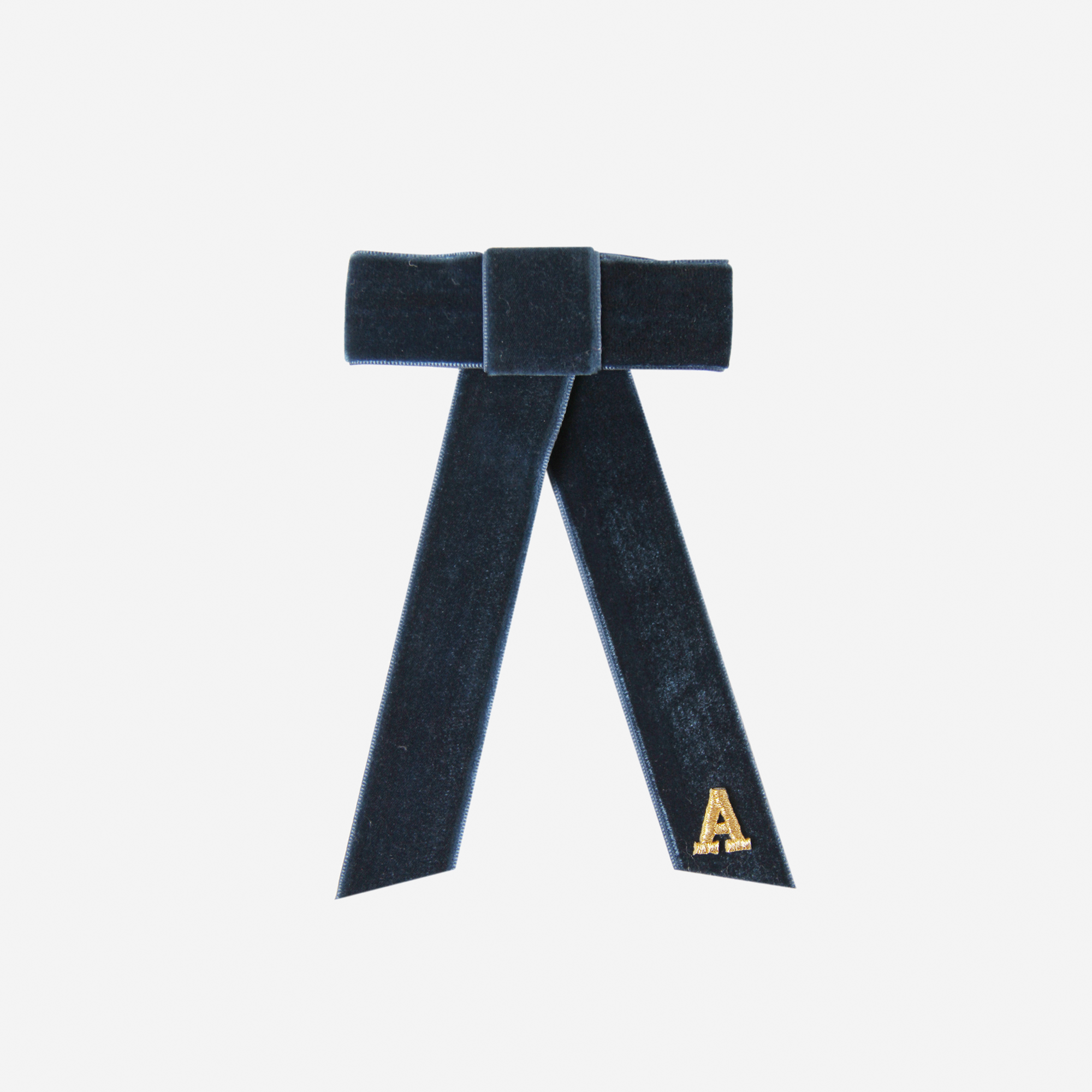 Navy blue velvet hair bow with a gold letter 'A' on an off white background