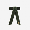 Green velvet hair bow with a gold 'T' on an off white background