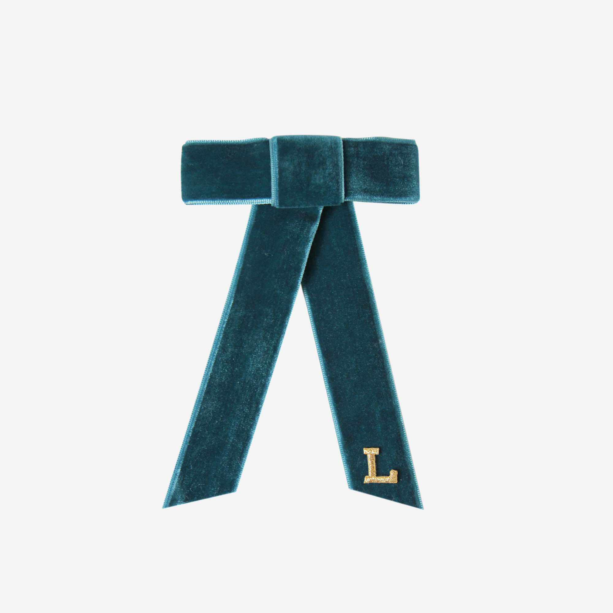 Teal velvet hair bow with a gold letter 'L' on an off white background