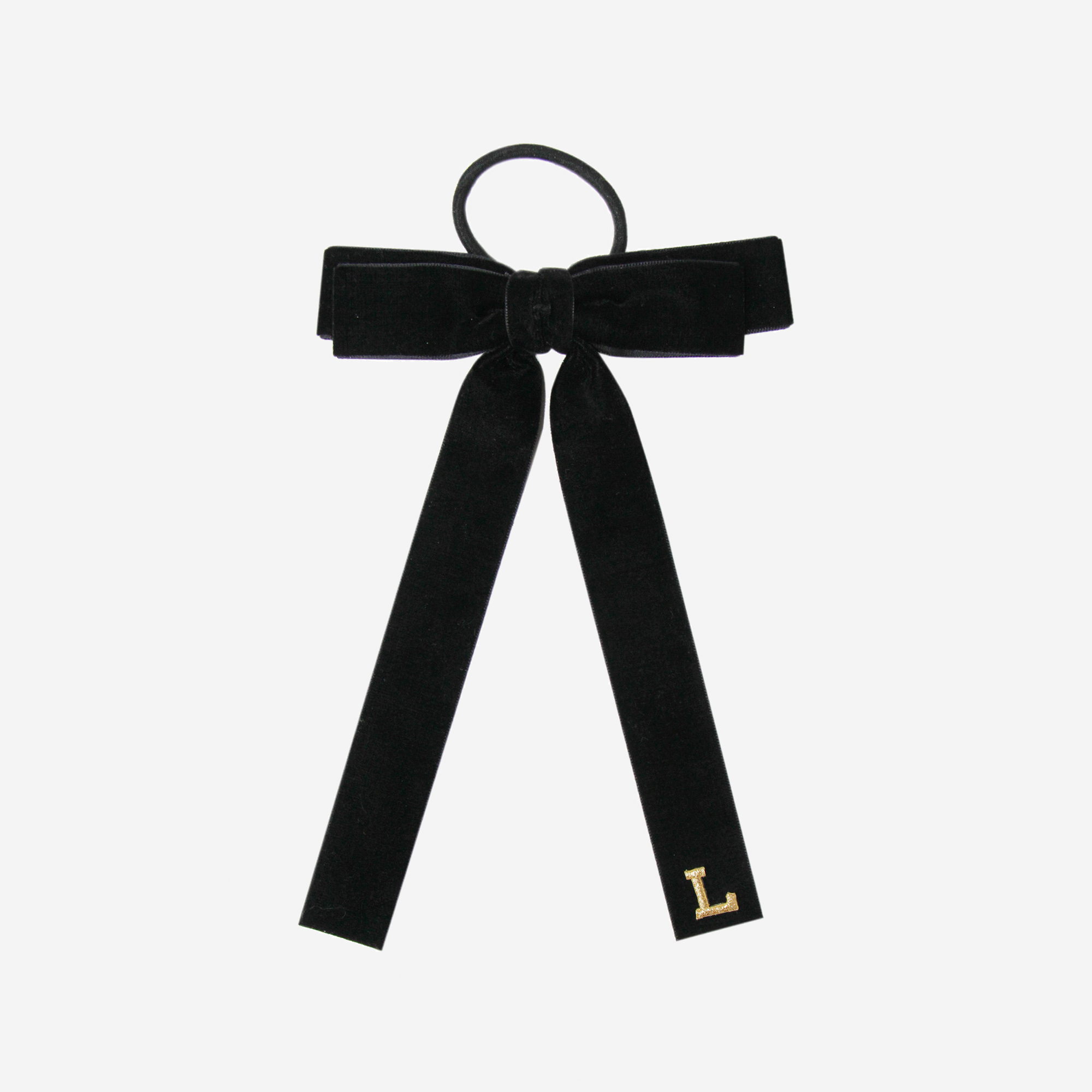 Black velvet  hair tie with a gold letter 'L' on an off white background
