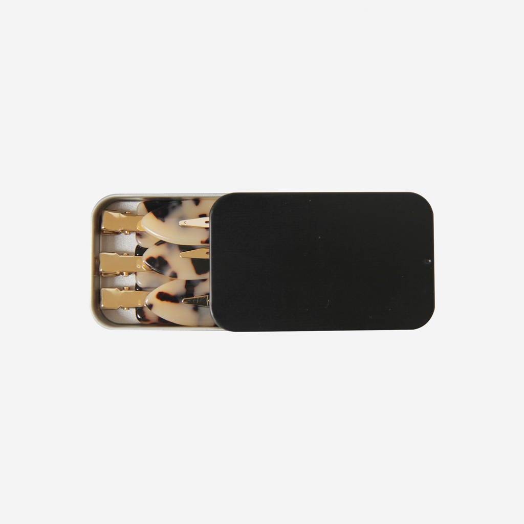 Set of 6 light tortoiseshell non crease hair clips  in a black tin, on an off white background