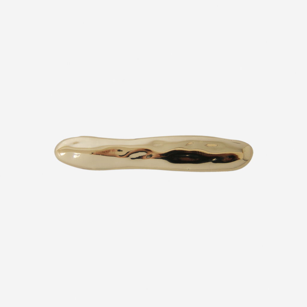 Gold hair clip with an organic shape on a white background