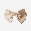 Large champagne hair bow on an off white background