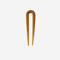 Small resin amber hairpin on an off white background