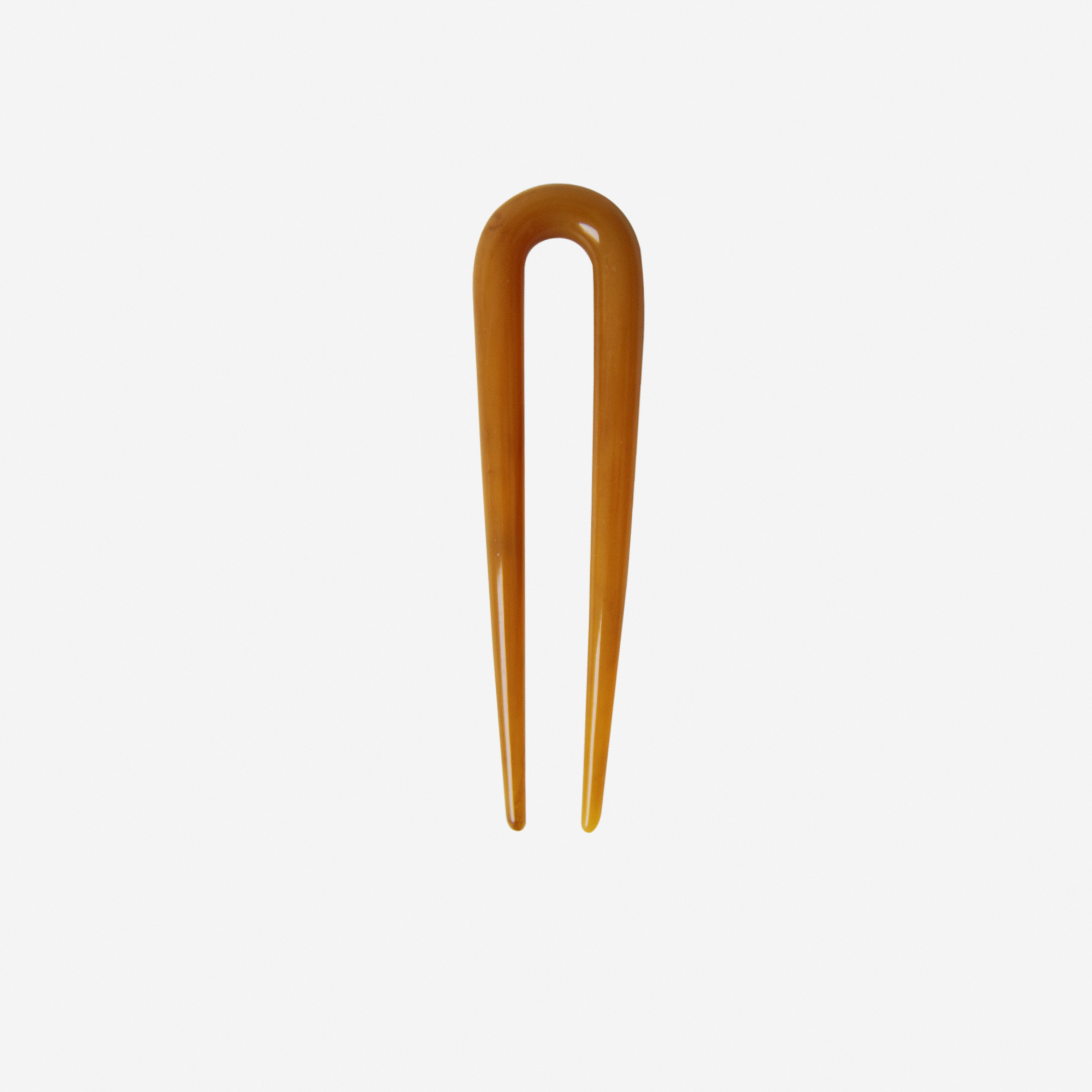 Small resin amber hairpin on an off white background