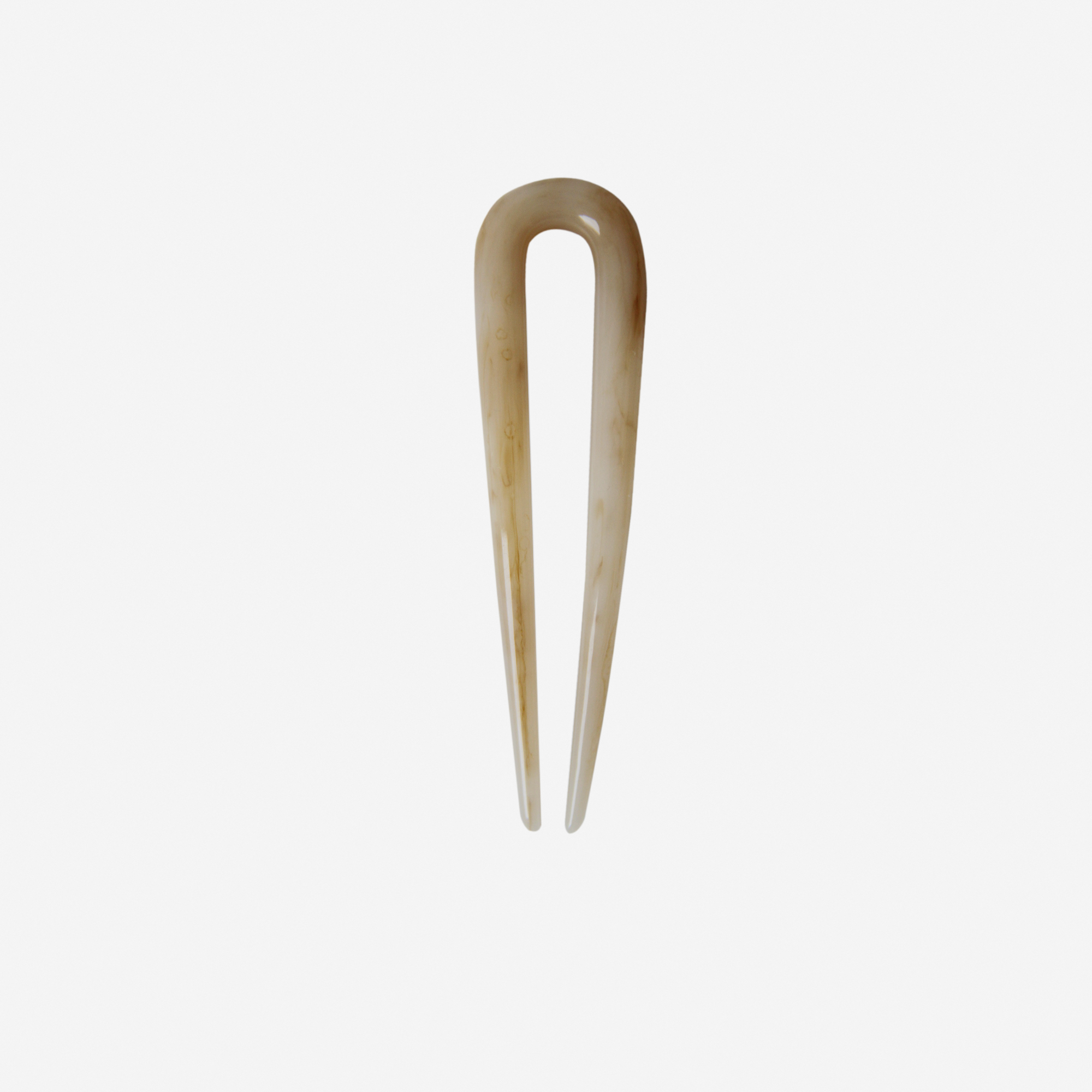 Small resin beige hairpin on an off white background