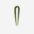 Small resin green hairpin on an off white background
