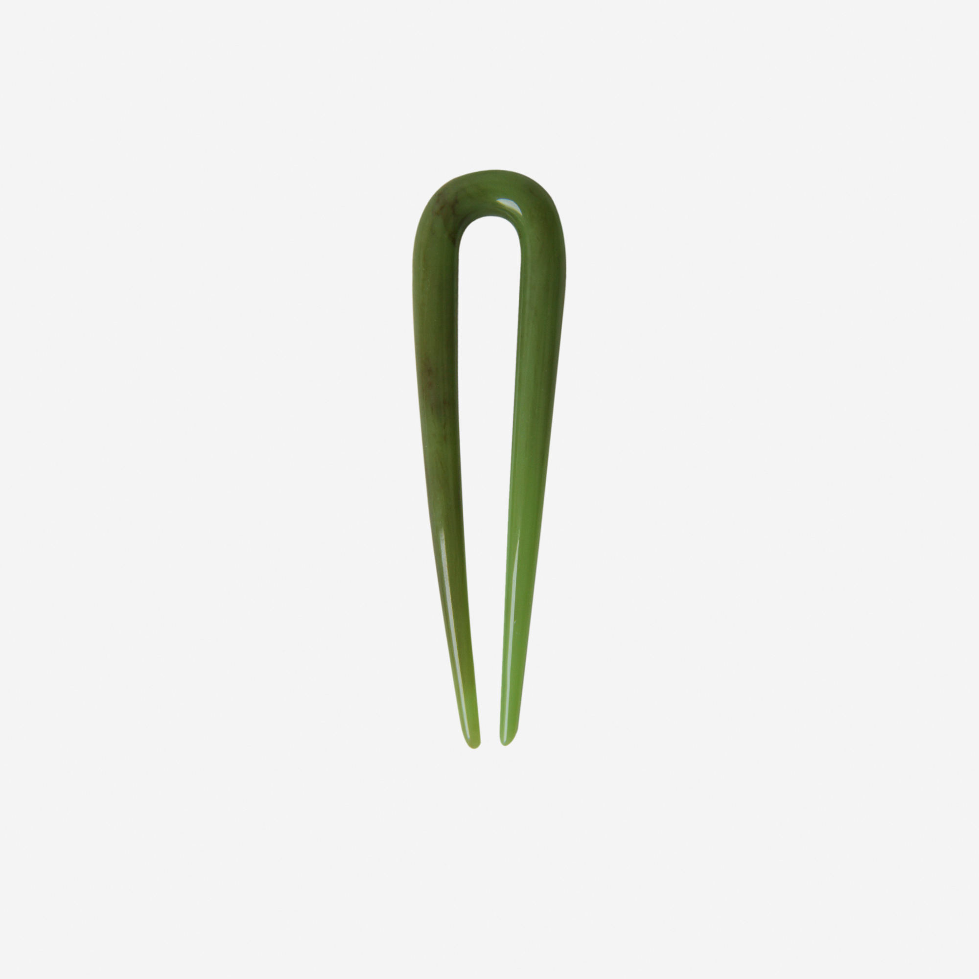 Small resin green hairpin on an off white background