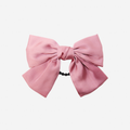 Pink bow hair tie on an off white background