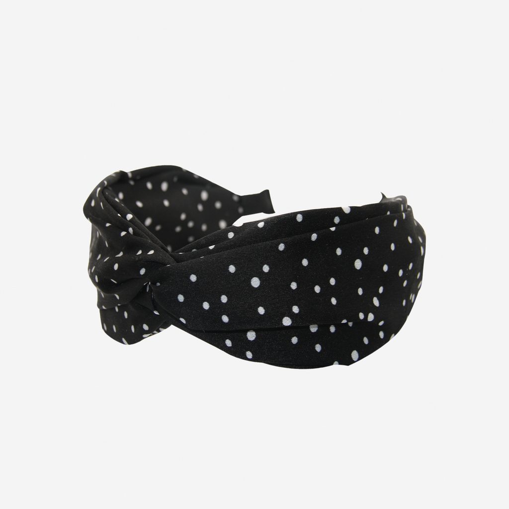 Black headband with white polka dots on an off white background