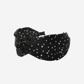 Black headband with white polka dots on an off white background