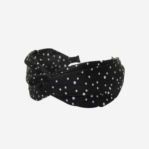 Black headband with white polka dots on an off white background