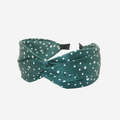 Green headband with white polka dots on an off white background