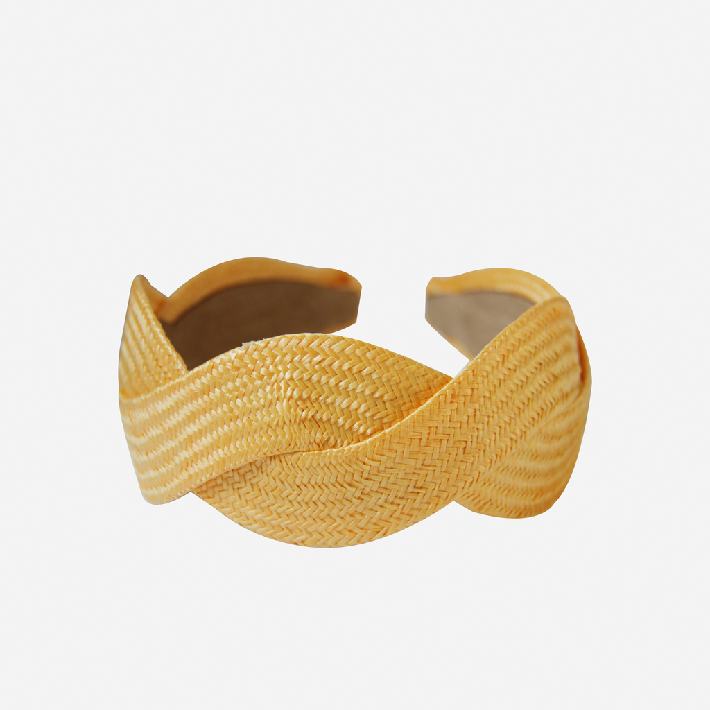Woven yellow raffia headband on an off white background