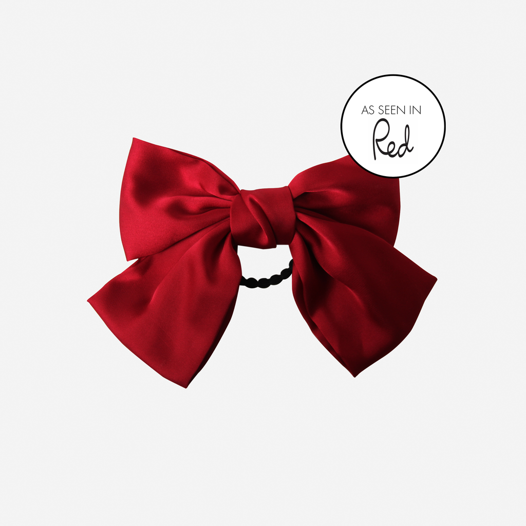 Red bow hair tie on an off white background