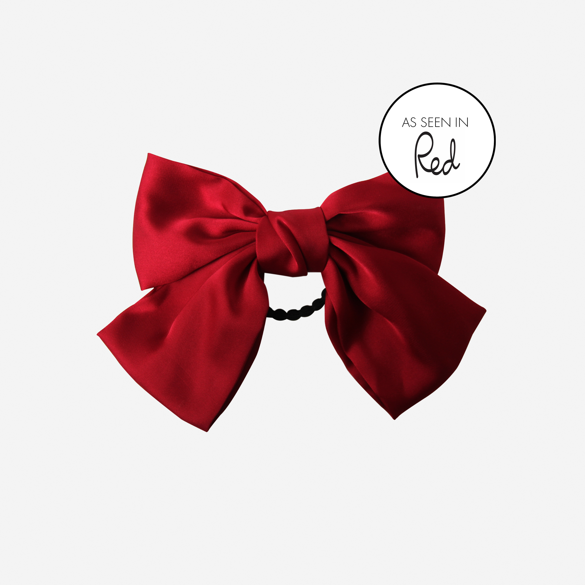 Red bow hair tie on an off white background