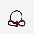 Red resin bow hair tie on an off white background