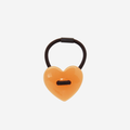 Mustard yellow heart shaped resin hair tie on an off white background