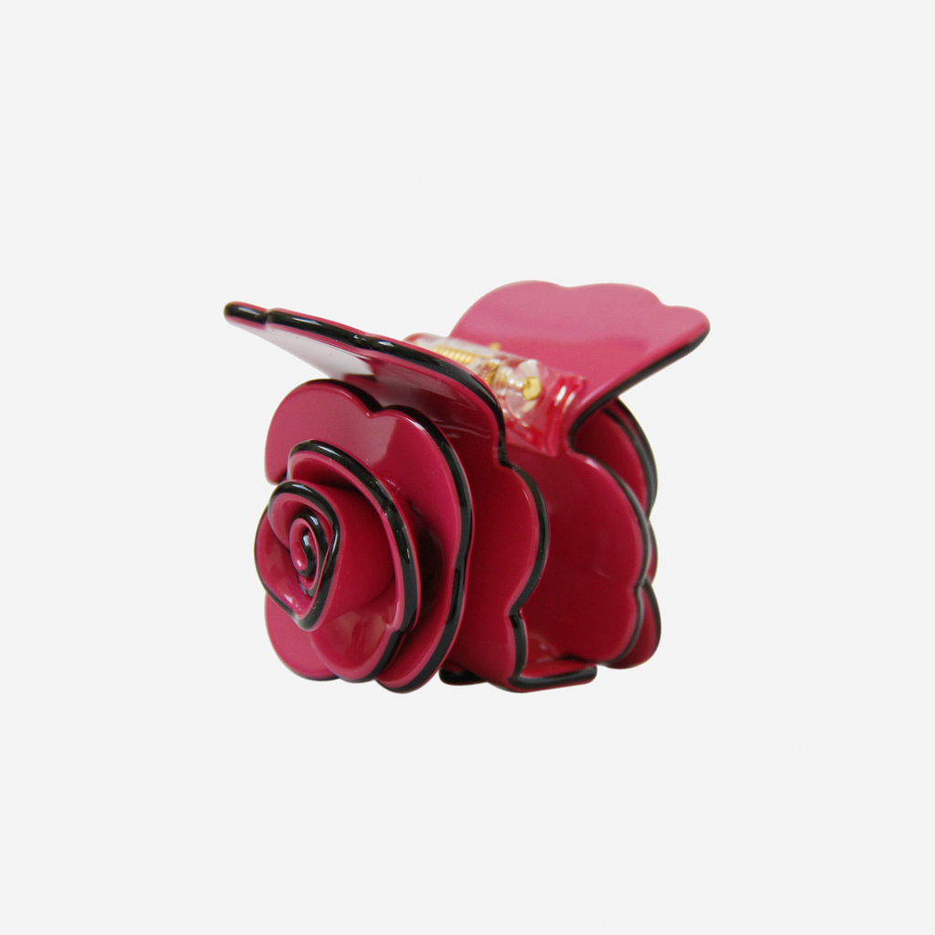 Crimson pink rose shaped hair claw on an off white background