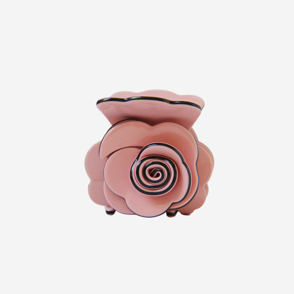 Pink rose shaped hair claw on an off white background