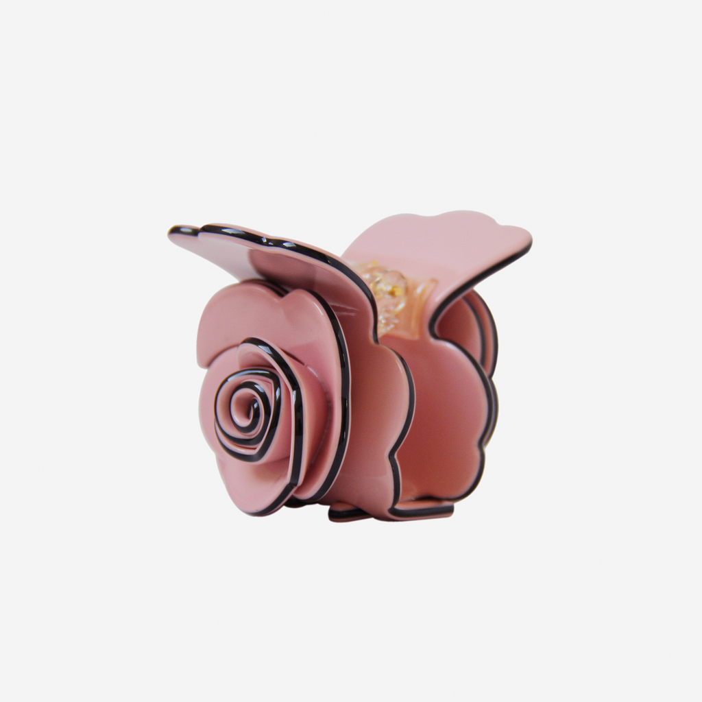 Pink rose shaped hair claw on an off white background