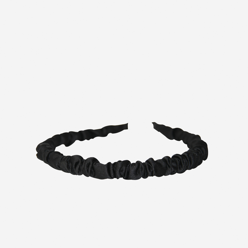 Narrow ruffle ruched black hairband on an off white background