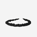 Narrow ruffle ruched black hairband on an off white background