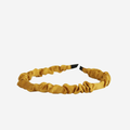 Narrow ruffle ruched mustard yellow hairband on an off white background