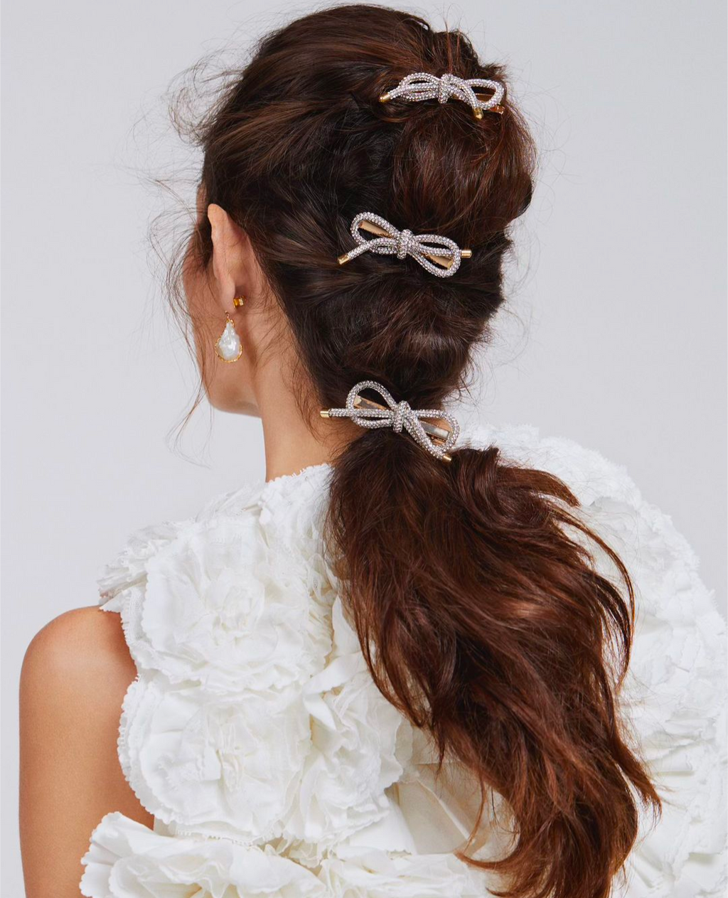 Three crystal bow hair clips styled in a up dp on a model with dark wavy hair, featured in Red Magazine