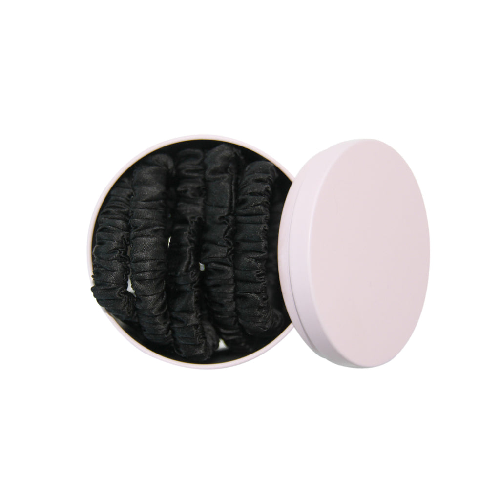 Set of 5 black silk hair ties in a pink tin on a white background