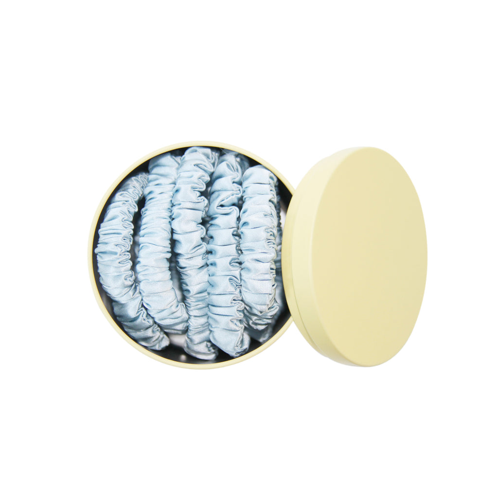 Set of 5 blue silk hair ties in a yellow tin on a white background