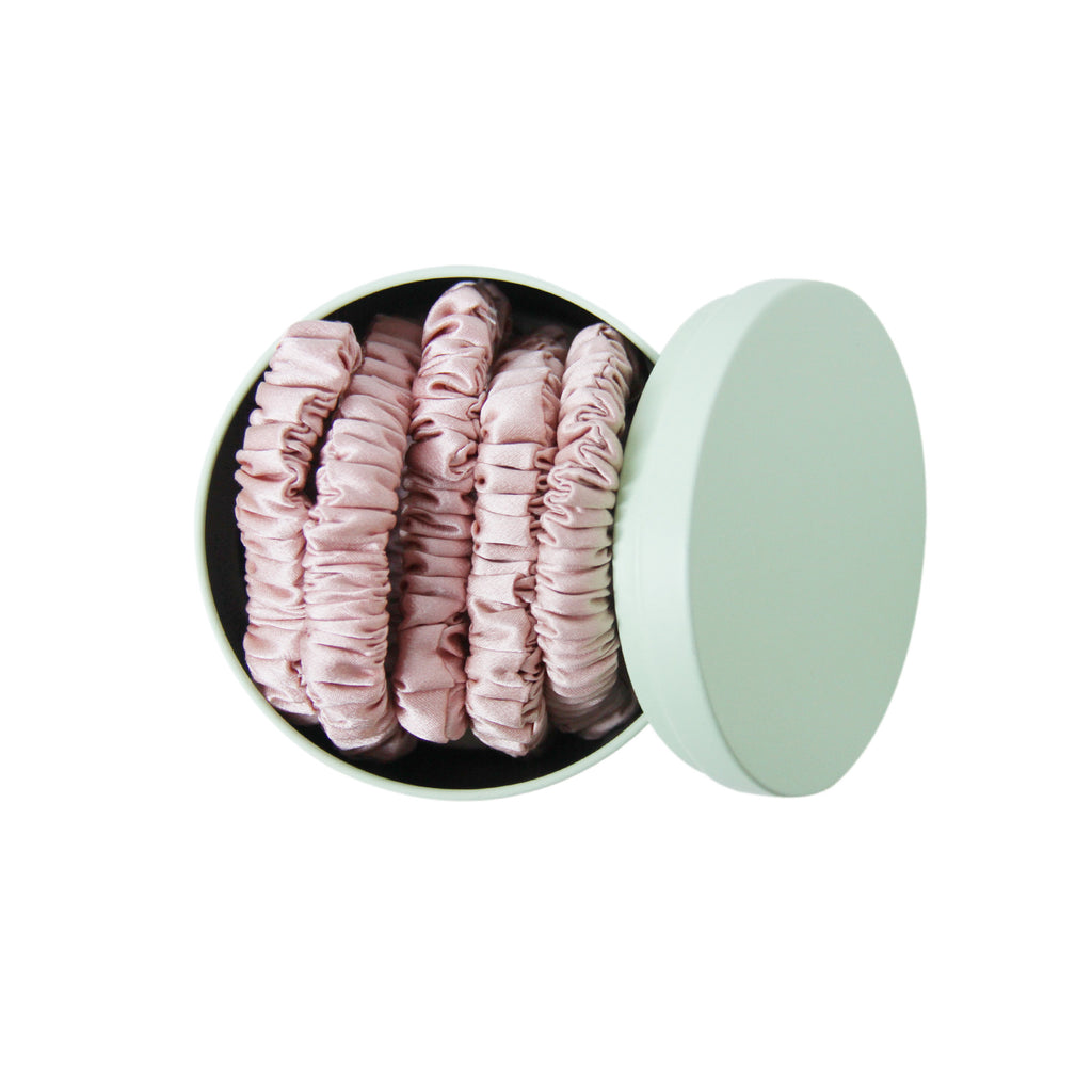 Set of 5 pink silk hair ties in a green tin on a white background