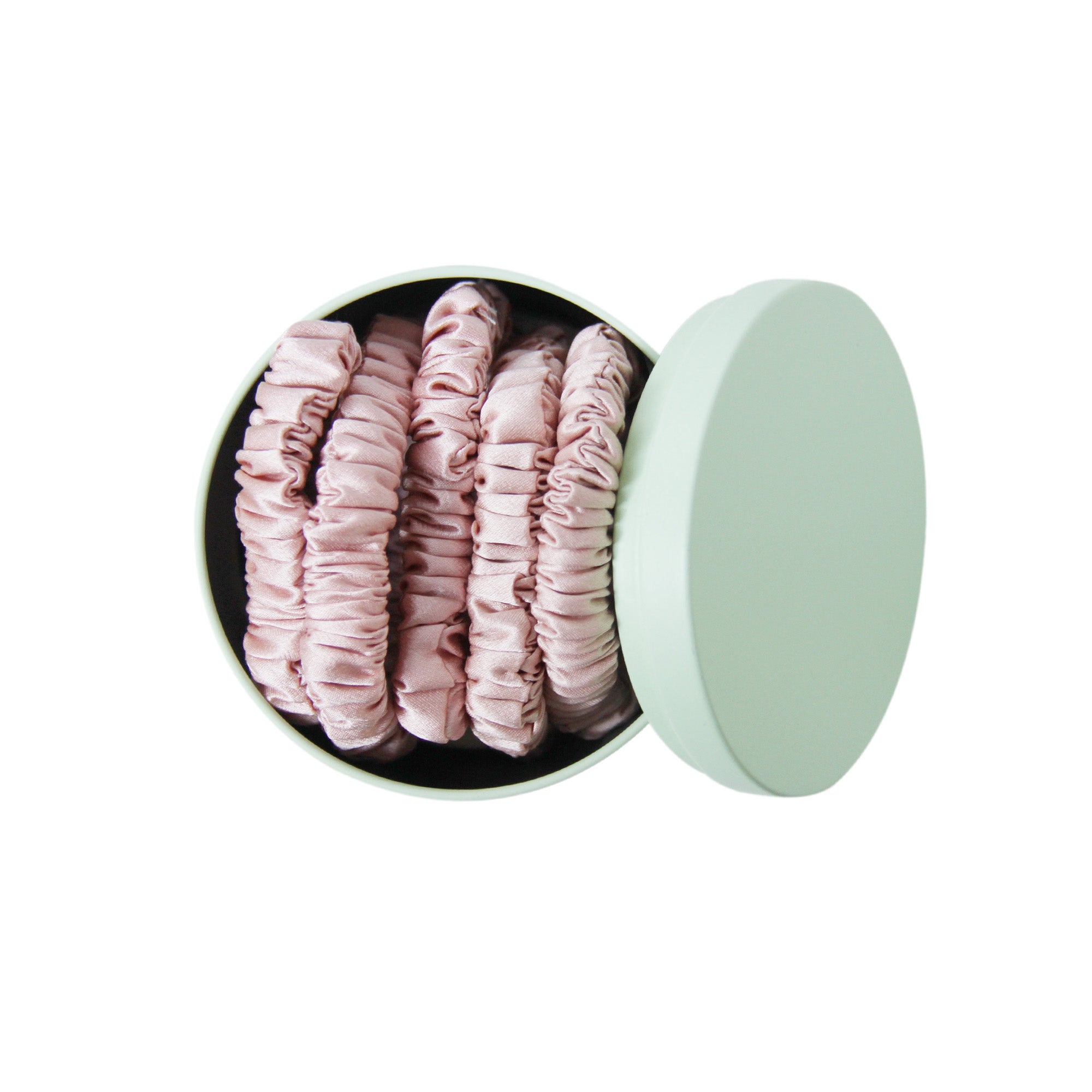 Set of 5 pink silk hair ties in a green tin on a white background