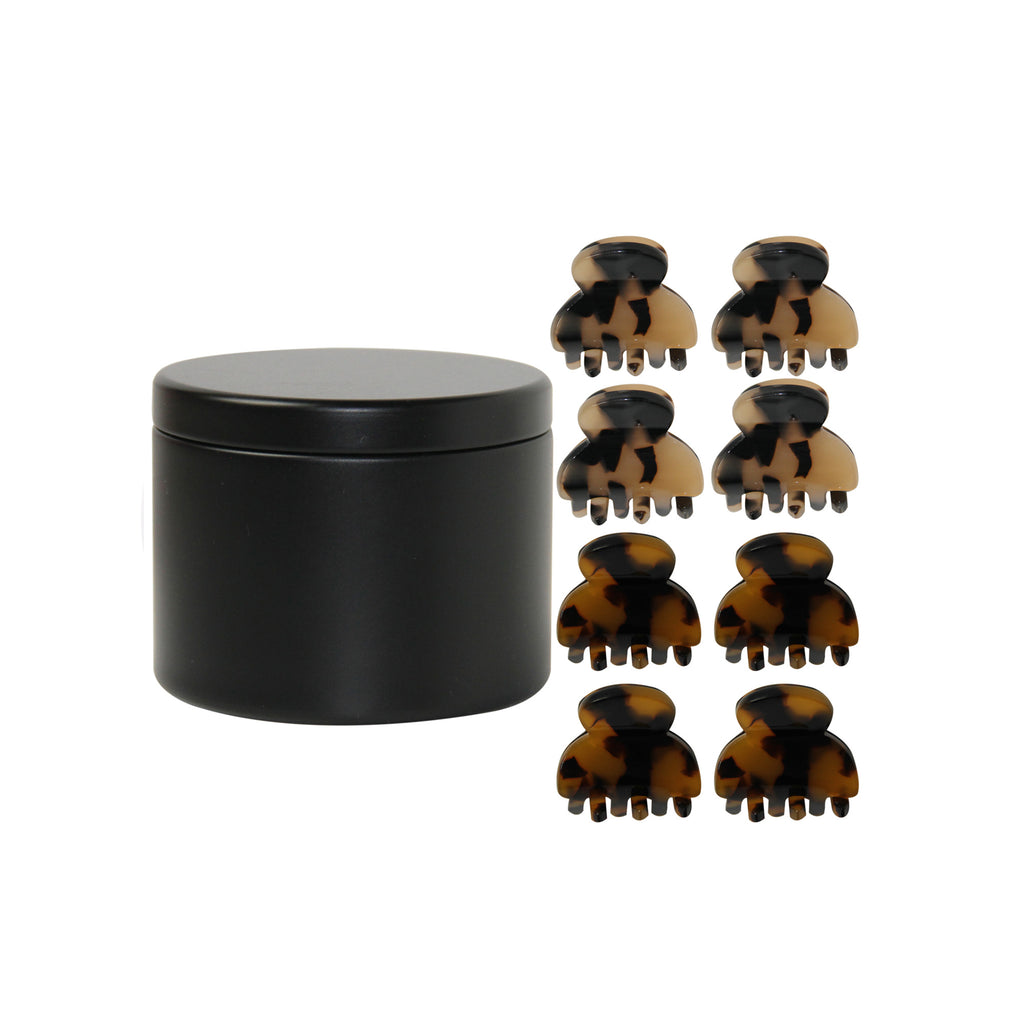 set of 8 mini tortoiseshell hair claws next to the black tin they come in on a white background