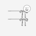 Set of 2 silver bow hair slides, featuring an as seen in red magazine logo, on an off white background
