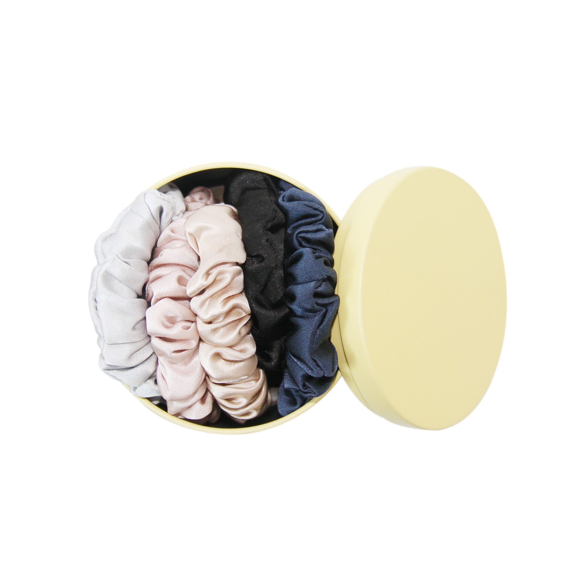 Set of 5 silk hair scrunchies of various colours in a yellow tin on a white background