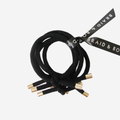 Set of 5 black hair elastics tied together with a black braid and brow ribbon on an off white background