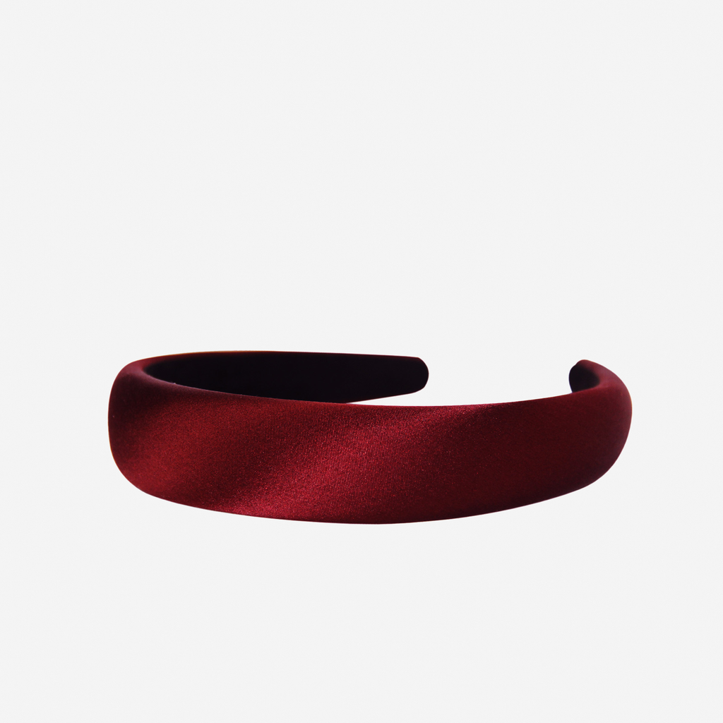Burgundy silk padded headband on an off white background