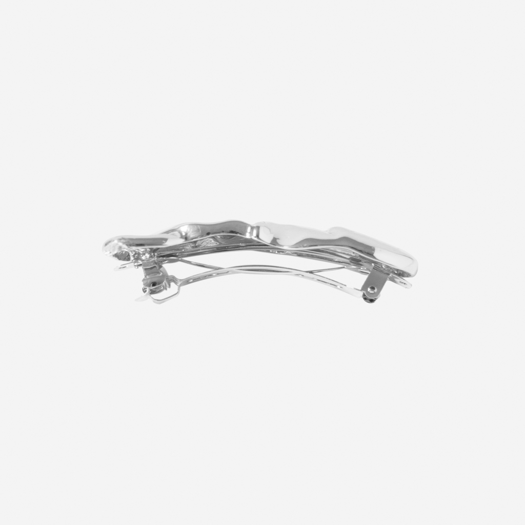 Silver folded hair clip, side view showing the hair barrette fastenng, on an off white background