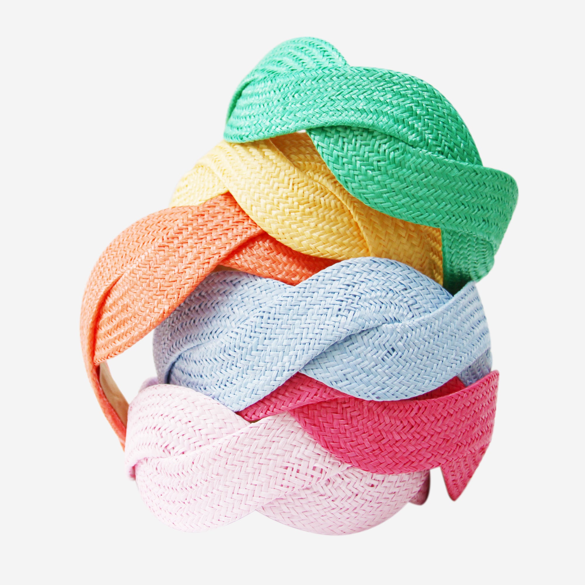 Colourful stack of raffia wave hairbands on an off white background