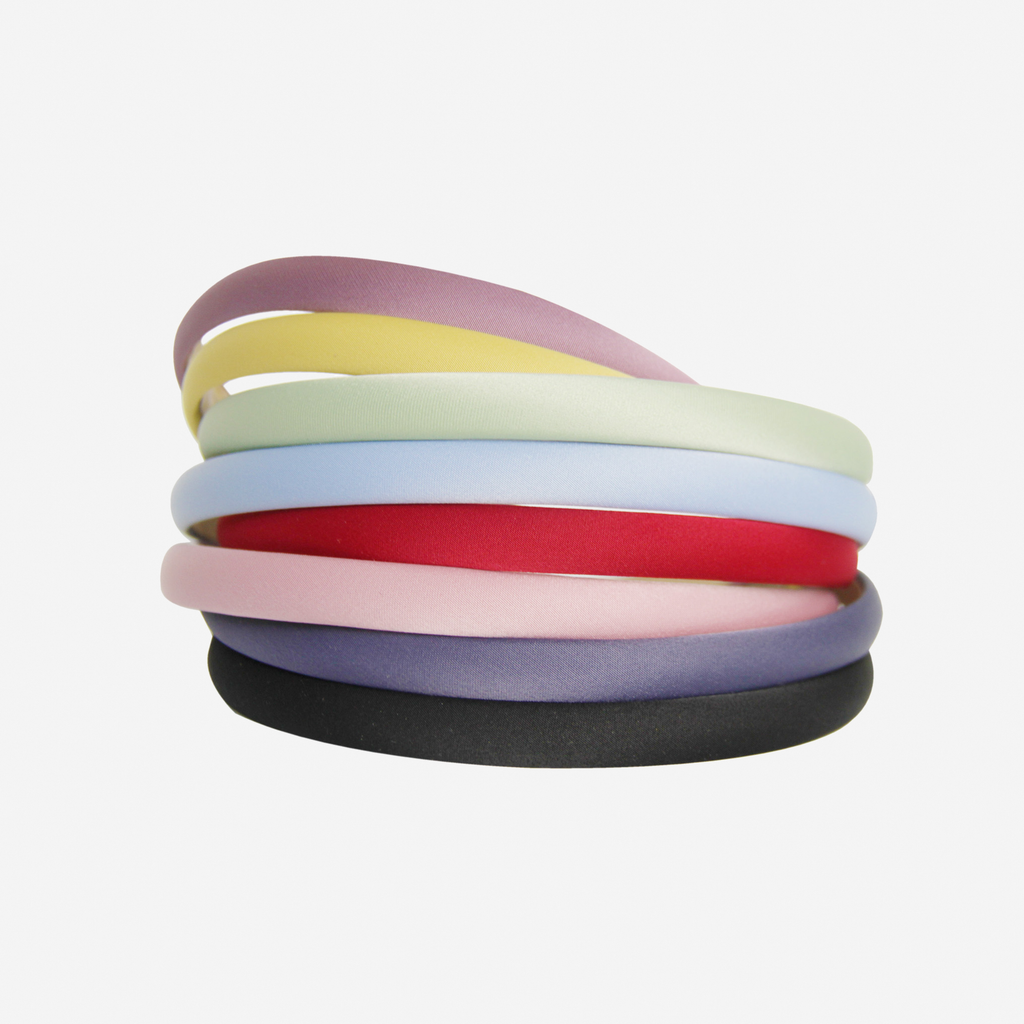 Stack of narrow colourful hairbands on an off white background