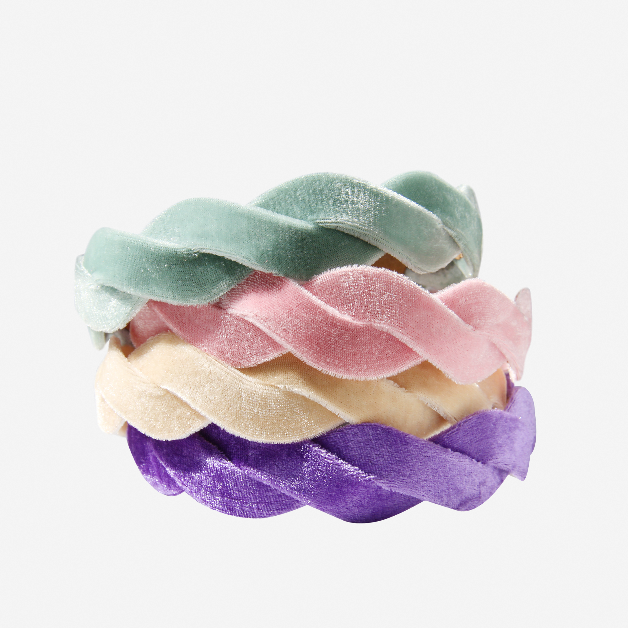 Stack of pastel coloured velvet wave hairbands on an off white background