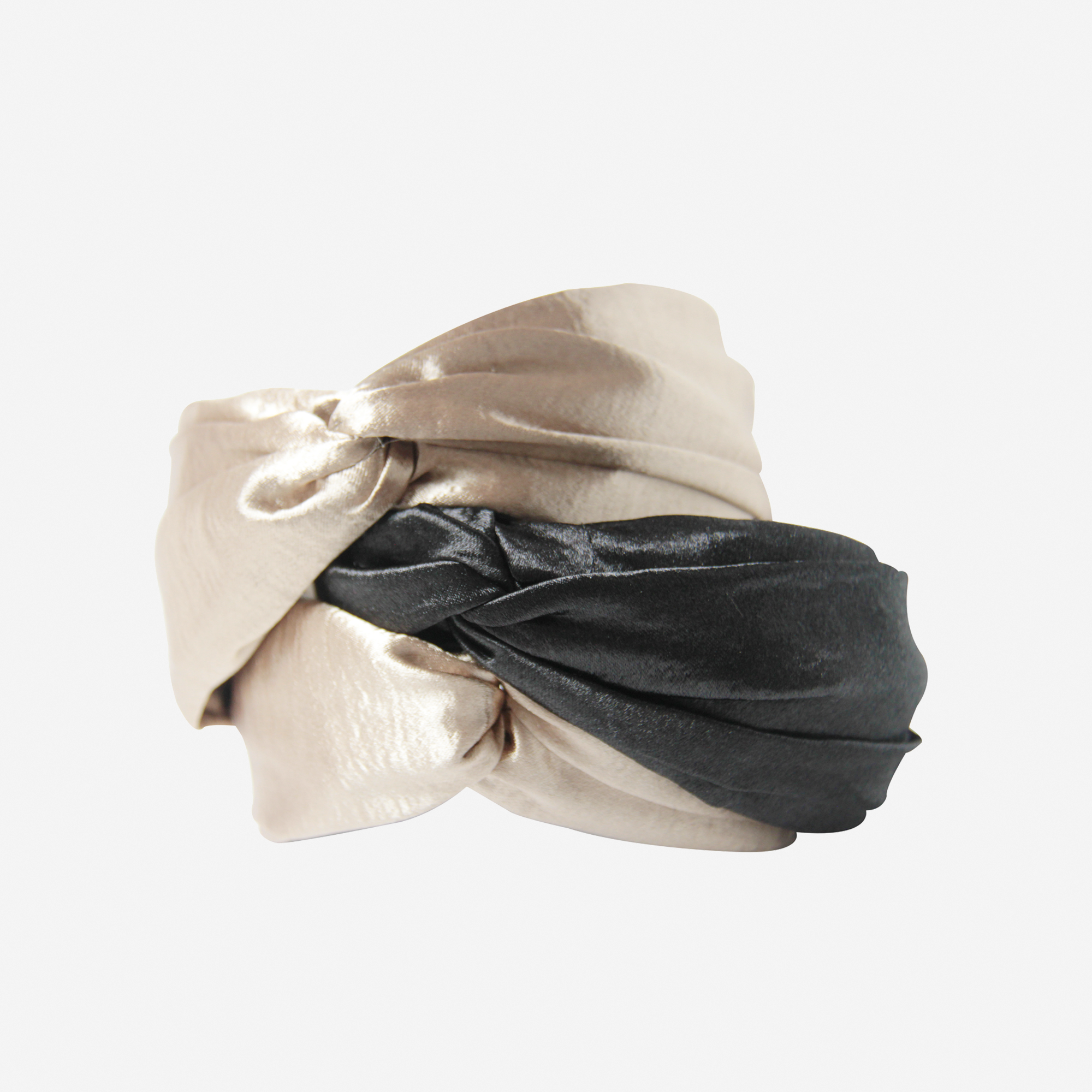 Stack of gold and black twist headbands on an off white background