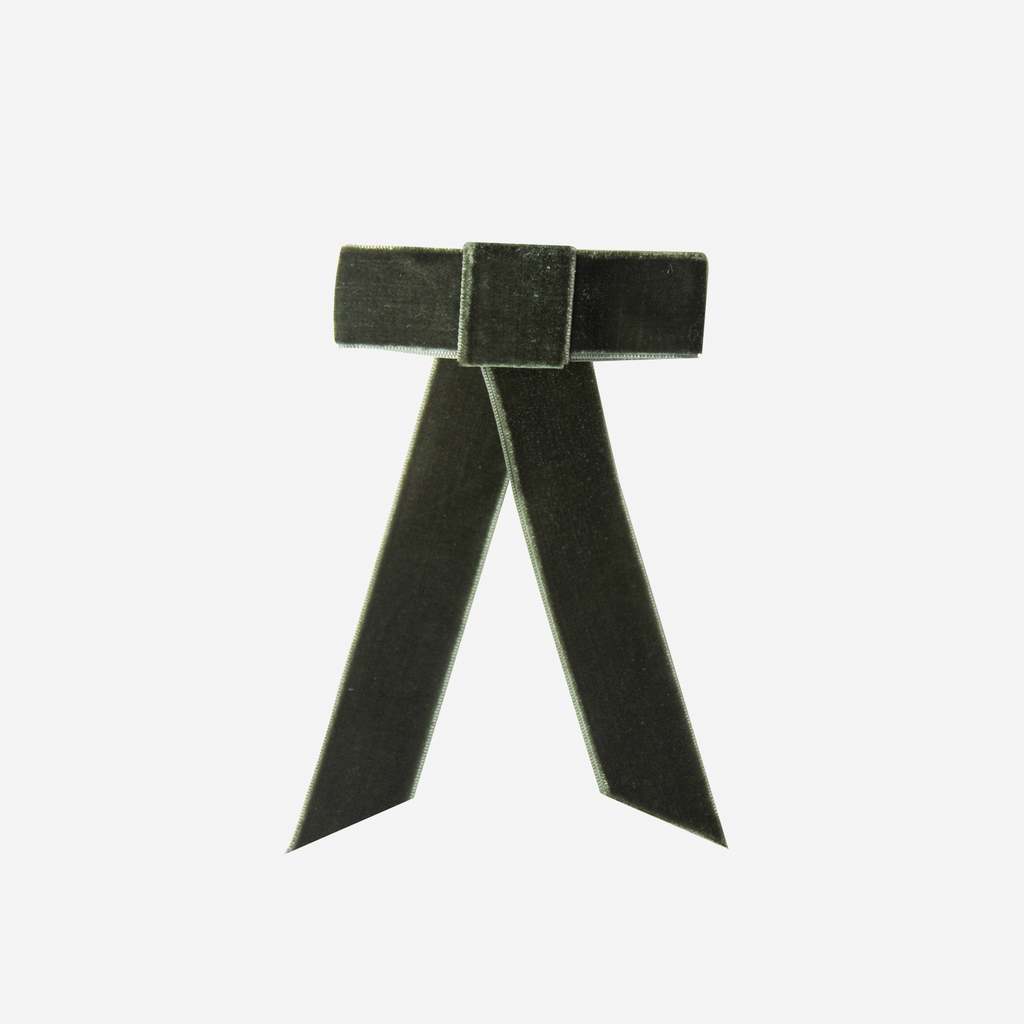Green velvet hair bow on an off white background