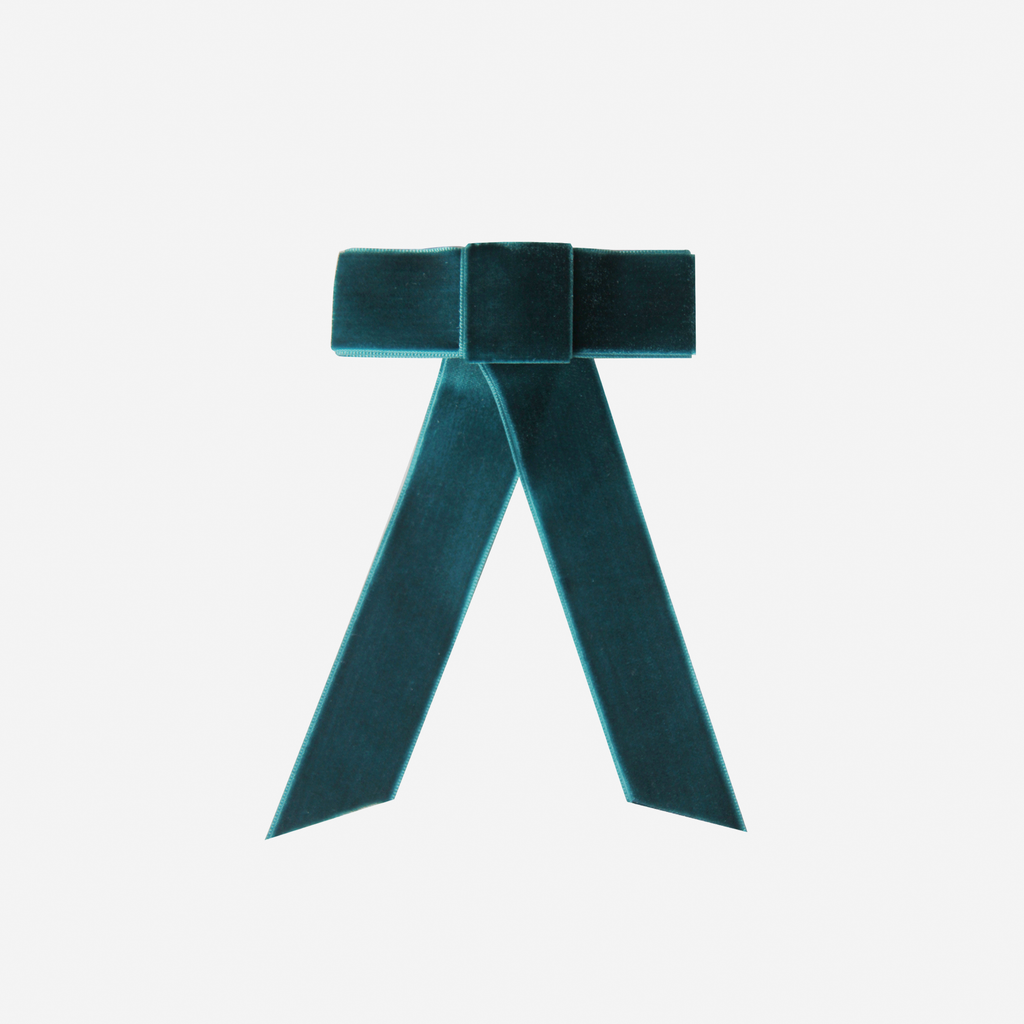 Teal velvet hair bow on an off white background