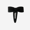 Black velvet bow hair clip on an off white background